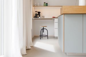 Blick am Kochblock vorbei auf einen Stahlhocker und die Arbeitsfläce aus Stahl.
