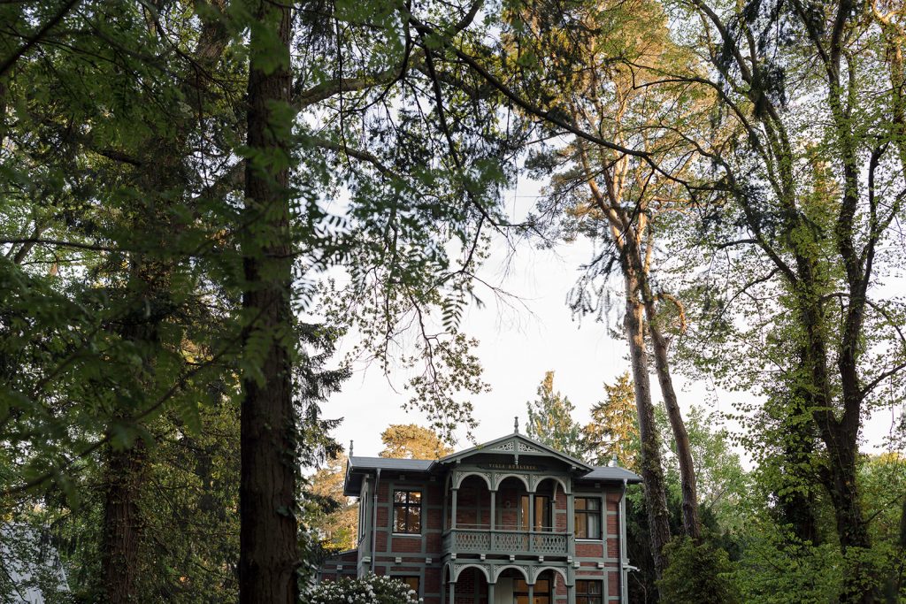 Die Villa Ruhleben, ein prächtiger Ziegelfachwerkbau aus 1890, umrahmt von großen Bäumen.